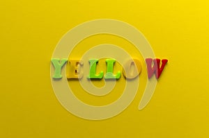 Word `yellow` from plastic colored magnet letters on yellow pape