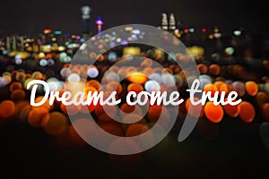 Wording Dreams come true with blurred background of night city and beautiful bokeh