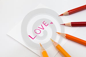 Wording Love in pink color with little heart on the small paper , encircle with color pencils in warm tone