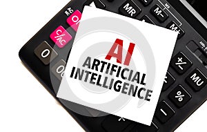 words AI - Artificial Intelligence on white sticker and calculator on white background
