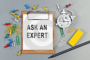 The words ask an expert written on a white notebook