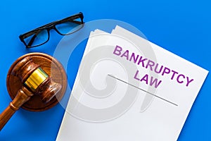 Words bankruptcy law written on the documents near judge gavel on blue background top view
