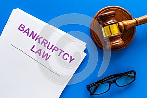 Words bankruptcy law written on the documents near judge gavel on blue background top view