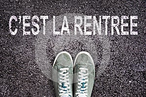 Words C`est la rentree meaning back to school written on asphalt road with sneakers shoes, high school and college con photo