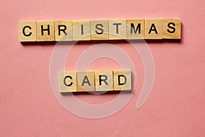 Words Christmas Card. Wooden blocks with inscription on pink background. The bulletin board. Concept of holiday-Christmas and New