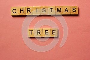 Words Christmas Tree. Wooden blocks with inscription on pink background. The bulletin board. Concept of holiday-Christmas and New