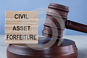 The words CIVIL ASSET FORFEITURE on wooden cubes against the background of the judge's gavel and stand