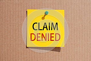 Words claim denied written on yellow square paper and pinned on craft paperboard