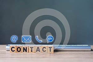 The words Contact written in wooden blocks placed in front of keyboard and a symbol mail, address, telephone, and text chat
