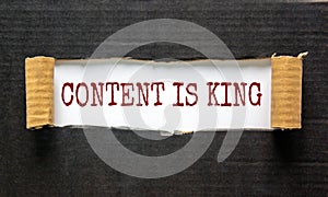 The words `content is king` appearing behind torn black paper. Beautiful background. Business concept