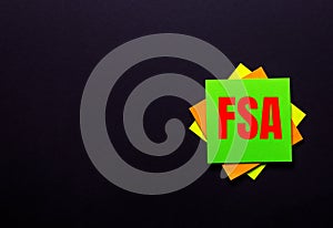The words FSA Flexible Spending Account on a bright sticker on a dark background. Copy space