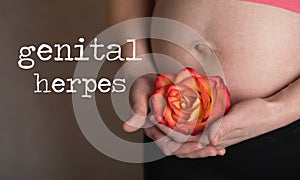 Words GENITAL HERPES. Young pregnant between 30 and 35 years old woman keeps rose blossom close to  her belly in the background