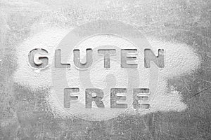 Words Gluten free written with flour on grey background, top view
