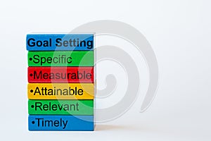 The words: Goal Setting, Specific, Measurable, Attainable, Relevant, Timely are written on colorful blocks photo