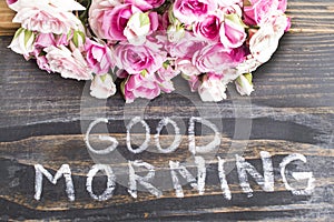 Words Good Morning with Pink Roses on a Rustic Wooden Background