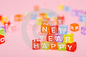 words happy new year made of colorful letters blocks on pink background. Flat lay, top view - holidays, winter, christmas and new