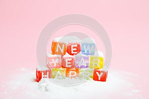 words happy new year made of colorful letters blocks on white snow and pink background. Flat lay, top view - holidays, winter, chr