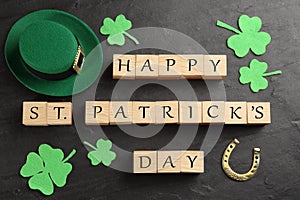 Words Happy St. Patrick`s day, hat and festive decor on black slate background, flat lay