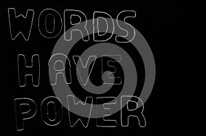 Words have power, silver text made from iron, metal letters. isolated on black background. Phrase words have power on the table. photo