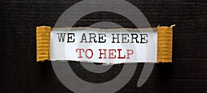 The words `we are here to help` appearing behind torn black paper. Beautiful background. Business concept