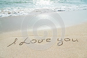 Words I love you outline on the wet sand