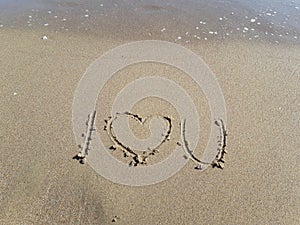 Words `I love you` written on wet sand at the sea