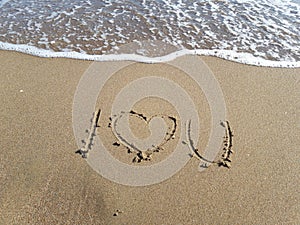 Words `I love you` written on wet sand at the sea