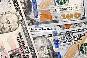 Words Income tax return on form 1040 and dollar bills close-up.