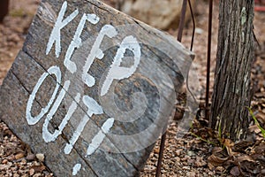 Words `keep out` painted on aged wooden board
