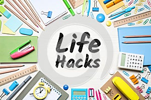 Words Life Hacks surrounded by stationery on white wooden table, flat lay