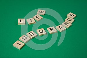Words life insurance by wooden blocks on green background.