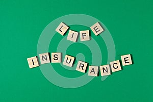 Words life insurance by wooden blocks on green background.