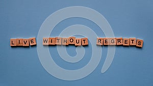 Words `Live without regrets` on a blue paper background.