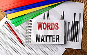 WORDS MATTER text on a notebook with pen, folder on a chart background