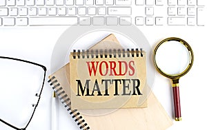 WORDS MATTER text in office notebook with keyboard, magnifier and glasses , business concept