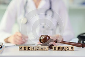 Words medical errors collected from wooden cubes with judge& x27;s gavel on table.