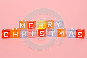 words merry christmas made of colorful blocks on pink background. Flat lay, top view - holidays, winter, christmas and new year ce