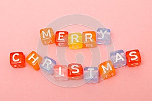 words merry christmas made of colorful blocks on pink background. Flat lay, top view - holidays, winter, christmas and new year ce