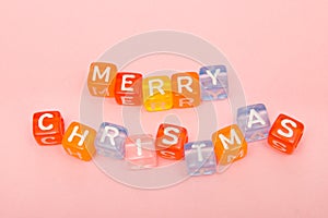 words merry christmas made of colorful blocks on pink background. Flat lay, top view - holidays, winter, christmas and new year ce