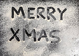 words Merry Xmas is written on a baking tray sprinkled with powdered sugar or flour