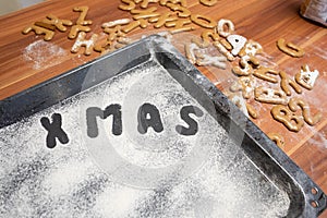 words Merry Xmas is written on a baking tray sprinkled with powdered sugar or flour