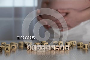 Words MUCUS DISCHARGE composed of wooden letters