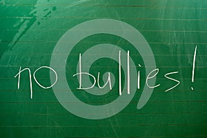 The words NO BULLIES written on the green school board
