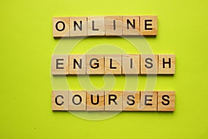 The words Online english courses are made up of wooden cubes on a yellow background. The concept of business and