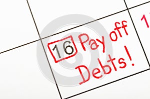 The words Pay off debts written on a calendar