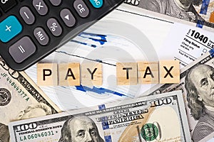 Words pay tax on form 1040, dollar bills and calculator.