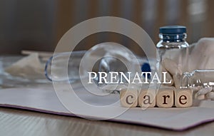 Words  PRENATAL CARE composed of wooden dices. Pills, documents and a pen in the background photo