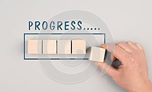 The words progress is standing over the loading bar, hand puts last cube to the upload