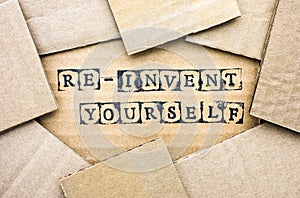 Words Re-invent Yourself make by black alphabet stamps on cardboard