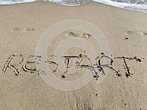 Words `Restart` written on wet sand at the sea